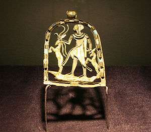 Gold pendant with a figure of a child standing on a crocodile grasping snakes and gazelles