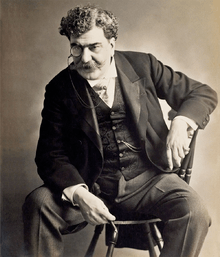 Black-and-white photographic portrait of Rafael Bordalo Pinheiro sitting on a chair.