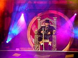 Raven wearing a leather jacket sitting on a throne at the top of a ramp