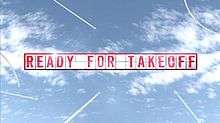 The words Ready for Take Off spelled out as separate letters on a display board, as aircraft in the distance fly around.