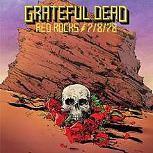 A skull and some roses on the ground, in front of a red sandstone outcropping