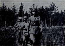 Black and white photograph of Red Army soldiers with rifles marching in a forest environment