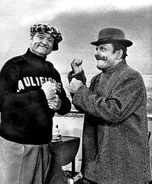 Two men. One the left is Red Skelton, smiling towards the camera. One the right is Terry-Thomas wearing a bowler hat, in a mock boxing stance
