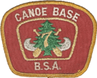 Patch with a red background and a gold border; the text Canoe Base BSA in the border; in the center a silver canoe superimposed with crossed paddles, a green pine tree and the number 7 in gold