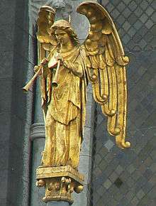 Robed figure of a standing winged angel with two straight trumpets, gazing down.