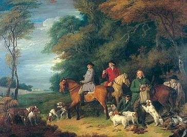 Five men and three horses at the edge of a wood along with a large group of dogs.