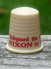 Beige thimble with red lettering, the visible part of which says "Safeguard the A..." and "NIXON for U...