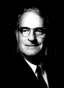 portrait of Richard Morse wearing eyeglasses, suit coat and necktie