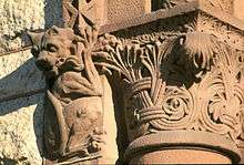 Close-up view of details on the building show a carved gargoyle hanging off the top of a column.