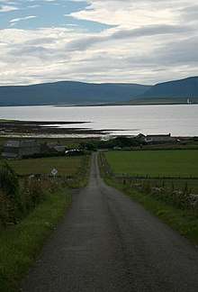 photo of road leading to sea loch with hills in the background