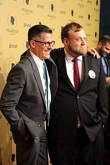 Two men are wearing suits; both are wearing glasses.