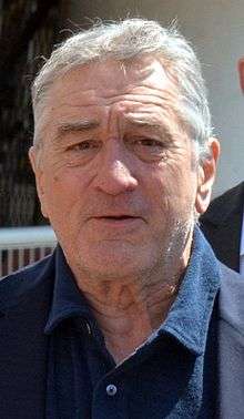 Photo of Robert De Niro—a white man of 70 years with white hair, wide nose, square face and small eyes, wearing a dark blue shirt—at the 2016 Cannes Film Festival.