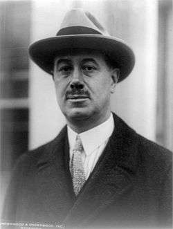 Black and white photograph of McCormick wearing a fedora and overcoat.