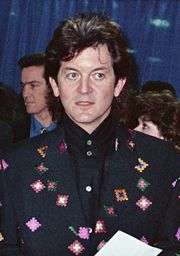 A man with long dark hair wearing a dark jacket
