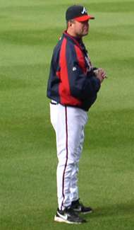 A man wearing a nylon navy blue and red warmup jacket and cap of the same colors