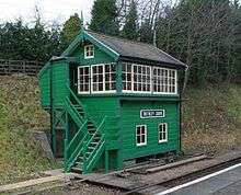 Green trackside building with stairs