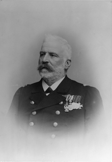 A black-and-white photo of an elderly naval officer in full dress uniform, with several medals pinned to his left breast.