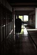 Man wearing a long dark robe about halfway down a corridor