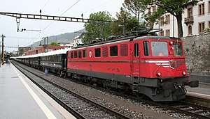 Red locomotive pulling a long passenger train