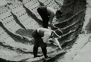 Black and white photograph showing two excavators working in the ship impression at Sutton Hoo