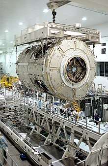 Interior of the SSPF, showing Node 2 being hoisted by overhead cranes
