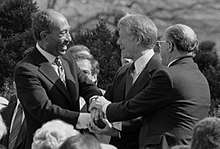 Anwar Sadat, Jimmy Carter, and Menachem Begin shaking hands on the White House grounds