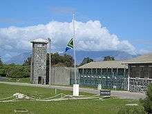 A view of a moderately fortified prison and a guard tower.