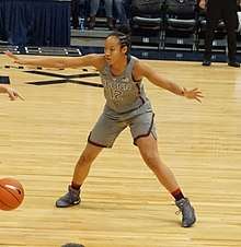 Young woman with limbs outstretched wearing Connecticut uniform