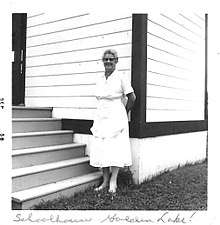 Black and white photograph of Sarah Lavalley standing in front of a school