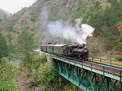 Steam engine pulling wooden passenger cars over a bridge