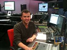 Scott Mills sitting at a radio station desk.