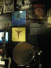 A museum exhibition of items associated with the 1990s Seattle music scene, including two Nirvana record album sleeves, a Soundgarden record sleeve, and instruments.