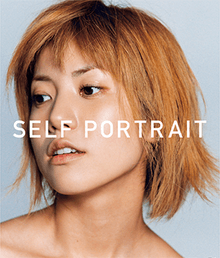 A tightly framed photograph of Hitomi with the title "Self Portrait" superimposed in a white, all caps, sans serif typography style. Against a blue backdrop; her strawberry blonde hair is cut in a choppy, mid-length bob style; her head and gaze are rotated away from the viewer.