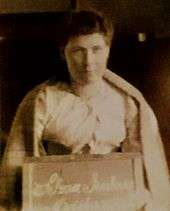 short-haired woman holding a board with "Selina Jenkins" written on it