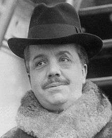plumpish middle-aged man with neat moustache, wearing a hat