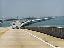 A view of a long bridge over water: a number of cars are visible in the left hand lane