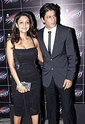 Shah Rukh Khan standing beside his wife Gauri at a party in 2012