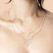 The neck and shoulders of a woman, tinted pink. A clear necklace has been digitally added to her.