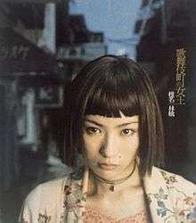 A woman with a straight fringe stares into the camera, and is surrounded by a Japanese drinking district.