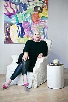 Seated portrait of Better Homes and Gardens Real Estate CEO Sherry Chris in front of an abstract painting.