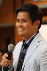 A close angle image of Alcasid smiling with a hand-held microphone in his right hand