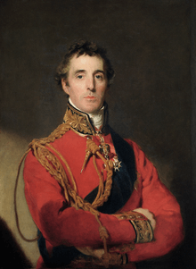 Painting shows a solemn, dark haired man with his arms folded. He wears a red military uniform with a high collar and loops of gold lace.