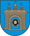 A coat of arms depicting a grey castle with three towers topped by crosses with a human head on the front door all on a blue background