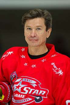 A man wearing a red hockey jersey looks at the camera.