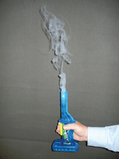 A hand grasping a small blue apparatus with white smoke emerging from its top