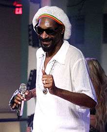 Snoop Dogg with a beanie in a white collared shirt