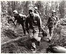 Soldiers of the 145th Infantry carry a wounded comrade off of Hill 700, Bougainville Island, March 1944.