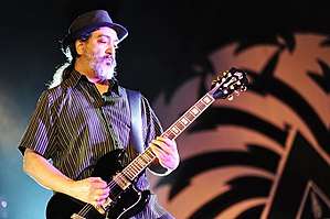 A male electric guitarist, Kim Thayil, onstage with an electric guitar. He has a beard.