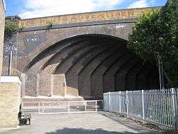 A wide brick arch spanning a narrow road at an oblique angle