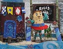 A costumed mascot of Mrs. Puff waving to an audience while standing on a float